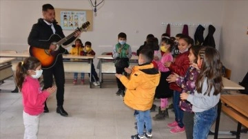 Şırnaklı okul müdürü gitarıyla karye köylük yer gezip öğrencilere musiki dinletisi sunuyor